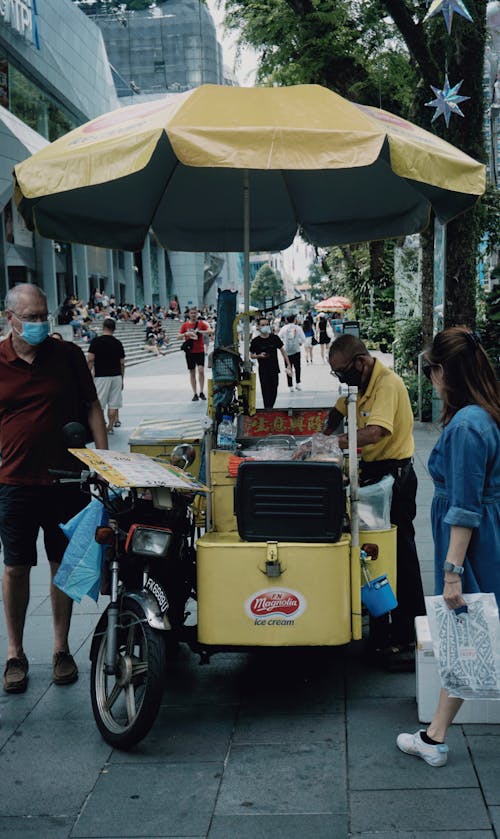 A Man Standing Beside the Food Cart