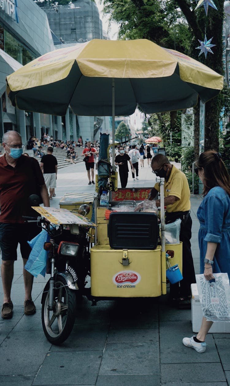 A Man Standing Beside The Food Cart