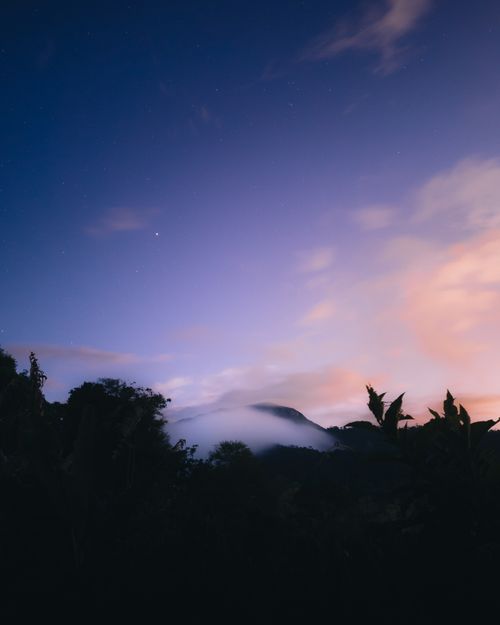 Free A serene twilight sky with silhouetted trees and misty mountains, perfect for dreamy landscapes. Stock Photo