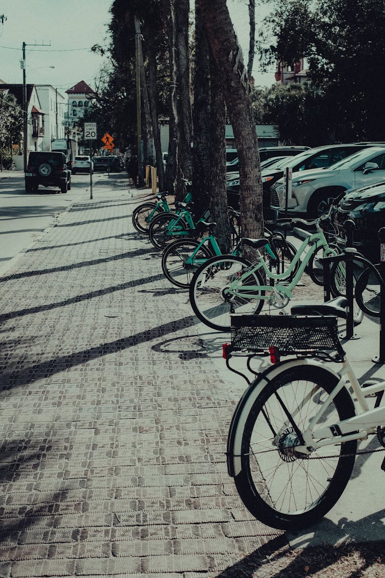 Bicycles And Cars Parked On The Street Side Of A City