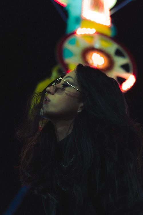 Free Captivating portrait of a woman at night with glowing neon festival lights in the background. Stock Photo