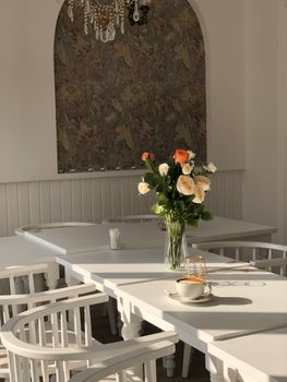Chic interior design featuring a dining table with roses and a cup of coffee in a well-lit space.