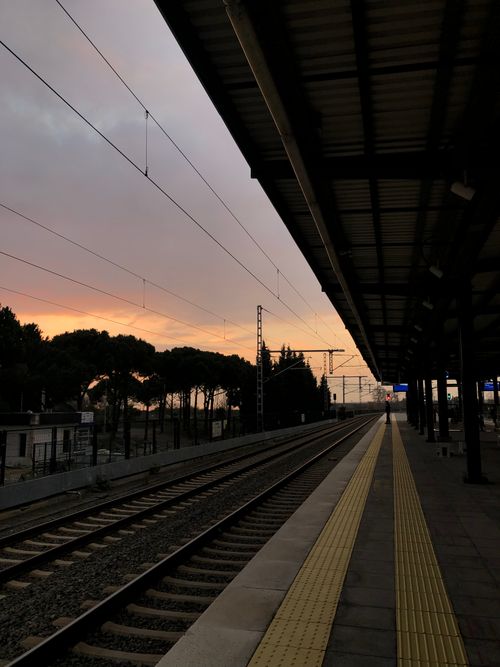 Free Empty train station platform with tracks at dusk, offering a serene urban travel scene. Stock Photo