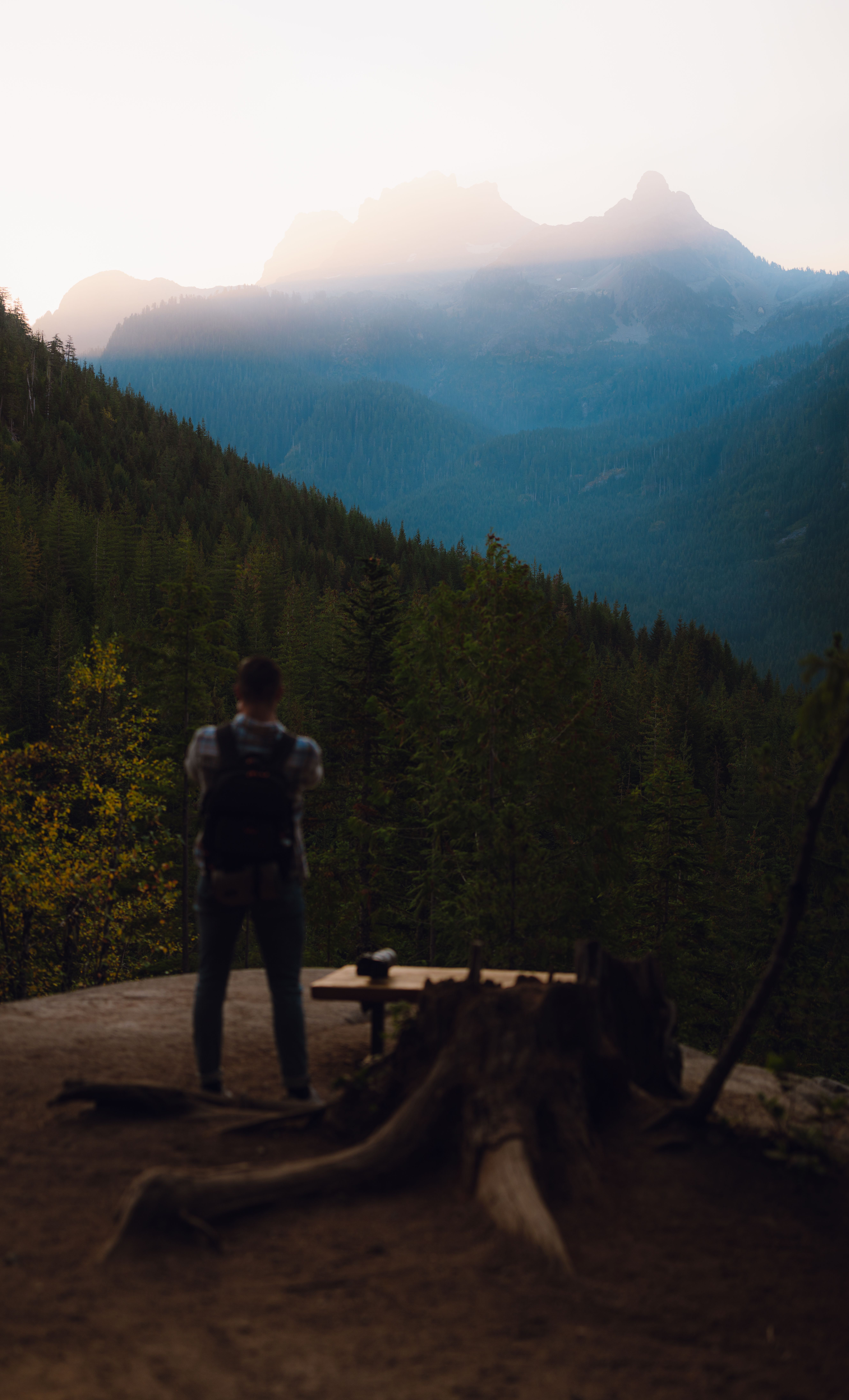 Sunrise over an Oregon state park trailhead sign with forest and mountains in the background