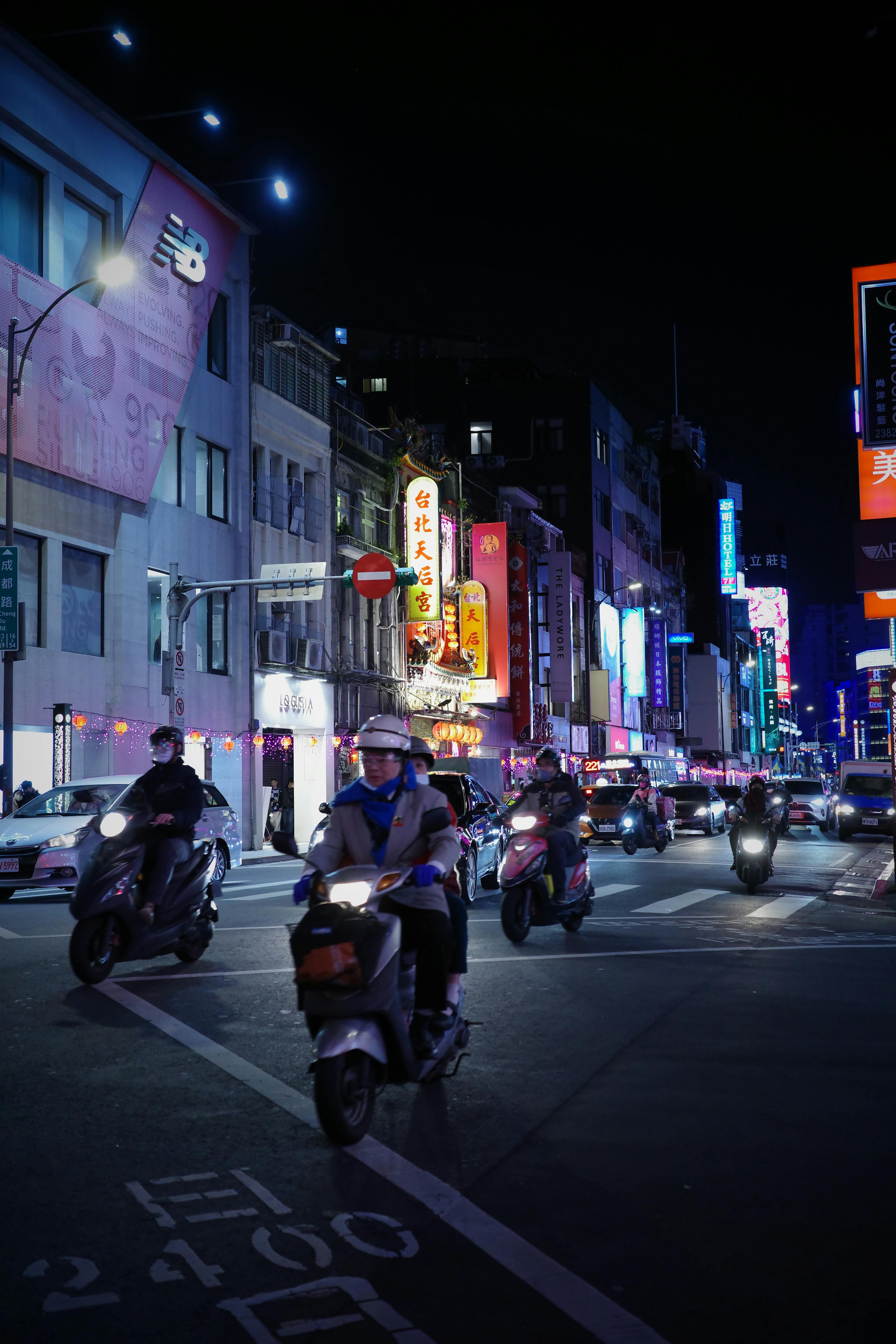 Night shot of pedestrians crossing road full of mopeds in busy