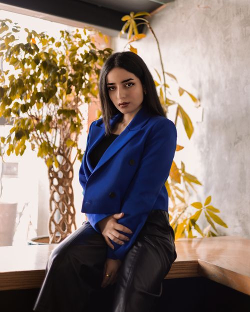 Free Young woman in stylish blue jacket poses indoors with an elegant and confident demeanor. Stock Photo