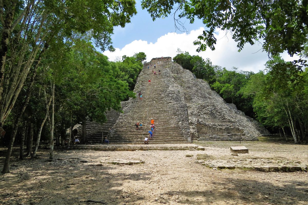Visitantes subiendo la antigua pirámide maya de Cobá rodeada de exuberante selva en México