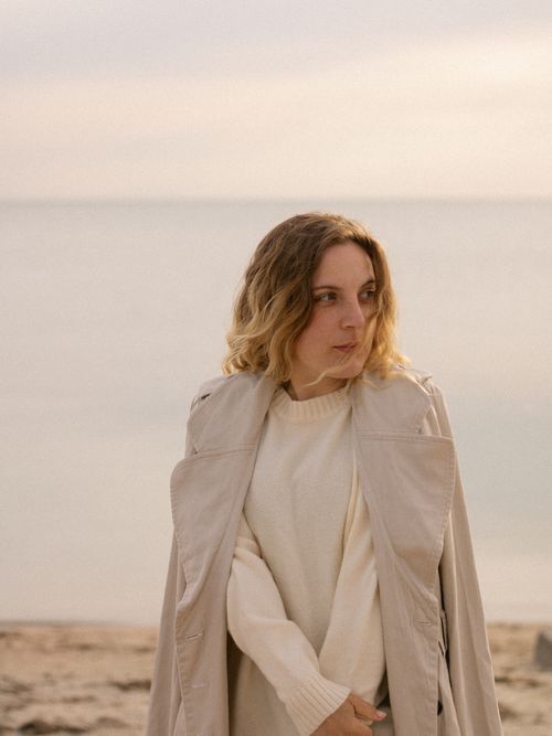 Free Fashionable woman in trench coat by the seaside at sunset. Stock Photo