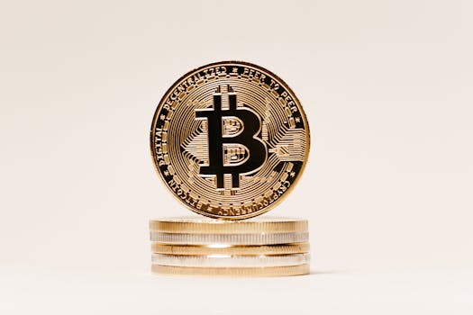 Close-up of a golden Bitcoin symbol coin on stacked coins with a white background, perfect for finance and technology content.
