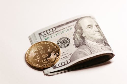 Dollar Bills and Bitcoin on White Surface