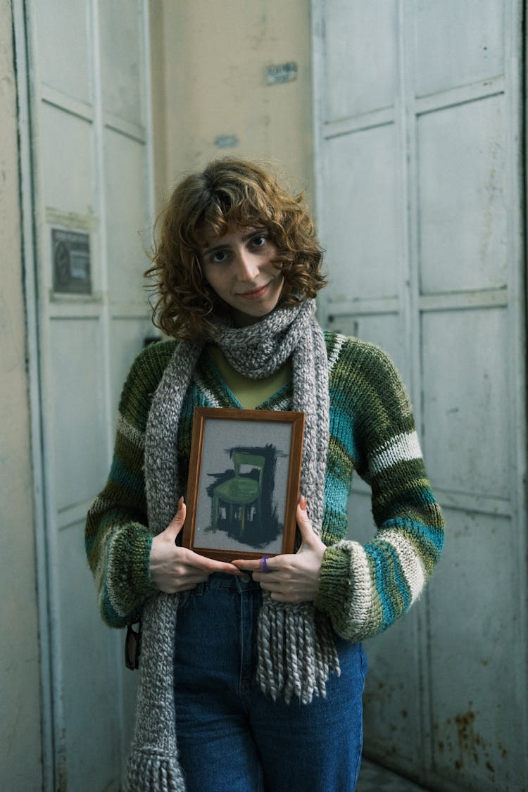 Woman In Scarf Holding Framed Picture Of A Chair