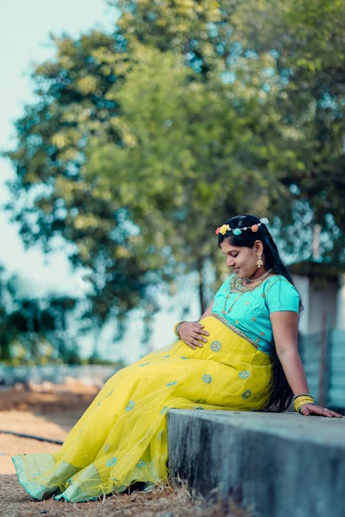 Happy Pregnant Woman Wearing a Maternity Dress Holding Her Tummy