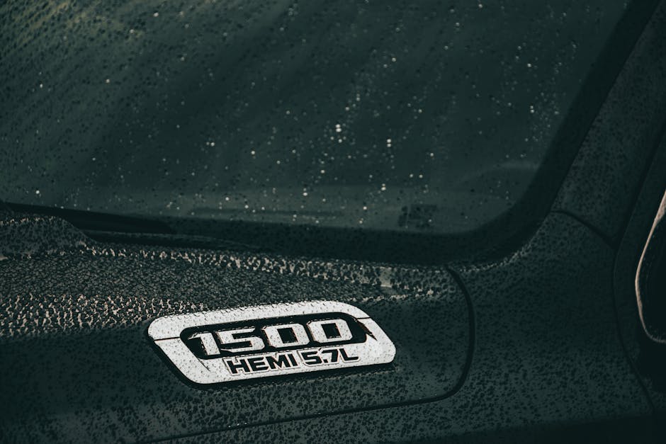 A close-up of a black Dodge Ram 1500 Hemi with rain droplets on the surface, showcasing automotive design.