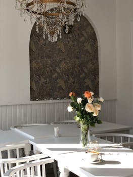 A charming display of flowers in a vase under an elegant chandelier in a restaurant.