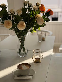 A delicate latte with a rose bouquet on a sunlit café table, evoking serenity.