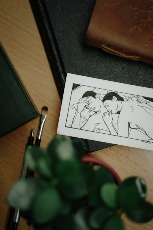 A drawing of a couple on a desk with a pen and a book