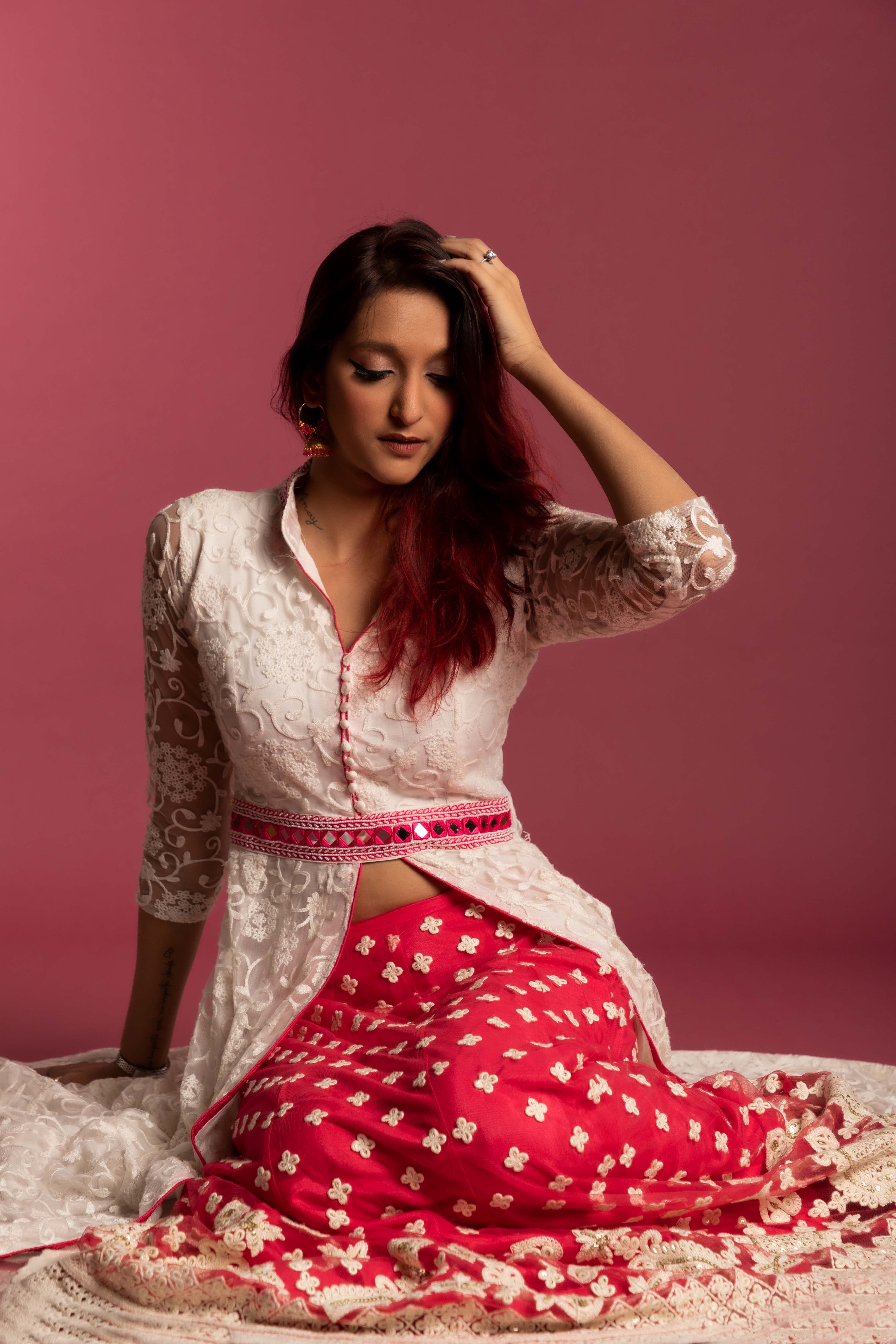 Woman in traditional dress posing elegantly in a studio with a warm tone.