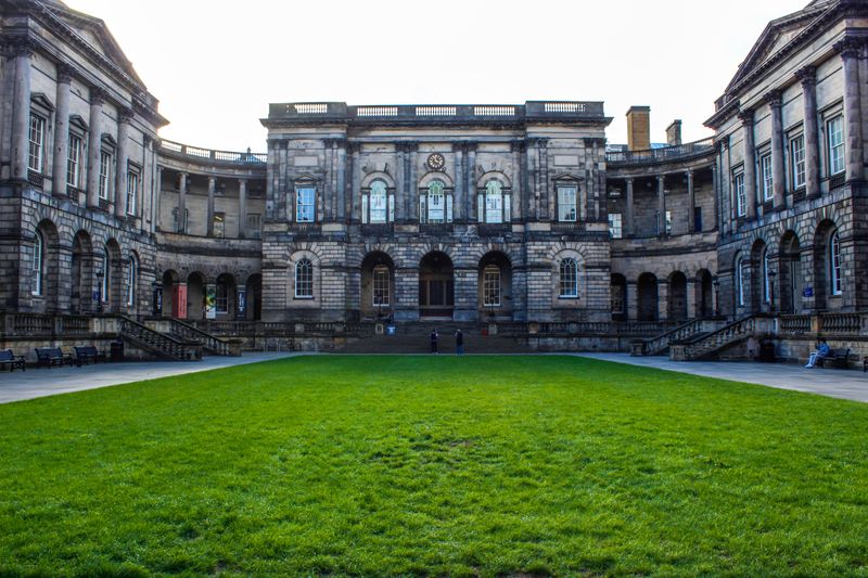 Fachada histórica da Edinburgh Law School com um pátio verde exuberante. Arquitetura icônica na Escócia.