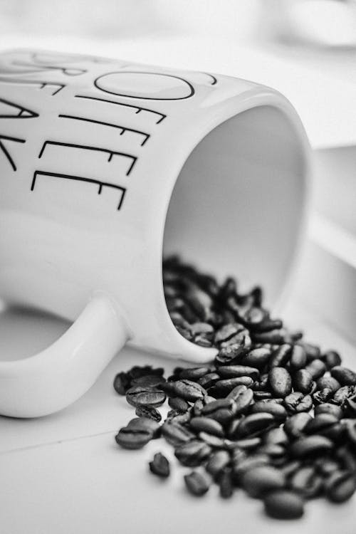 Grayscale Photo of Coffee Beans on Coffee Cup