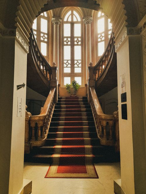 Free Luxurious curved staircase with red carpet in an elegant historical interior setting. Stock Photo