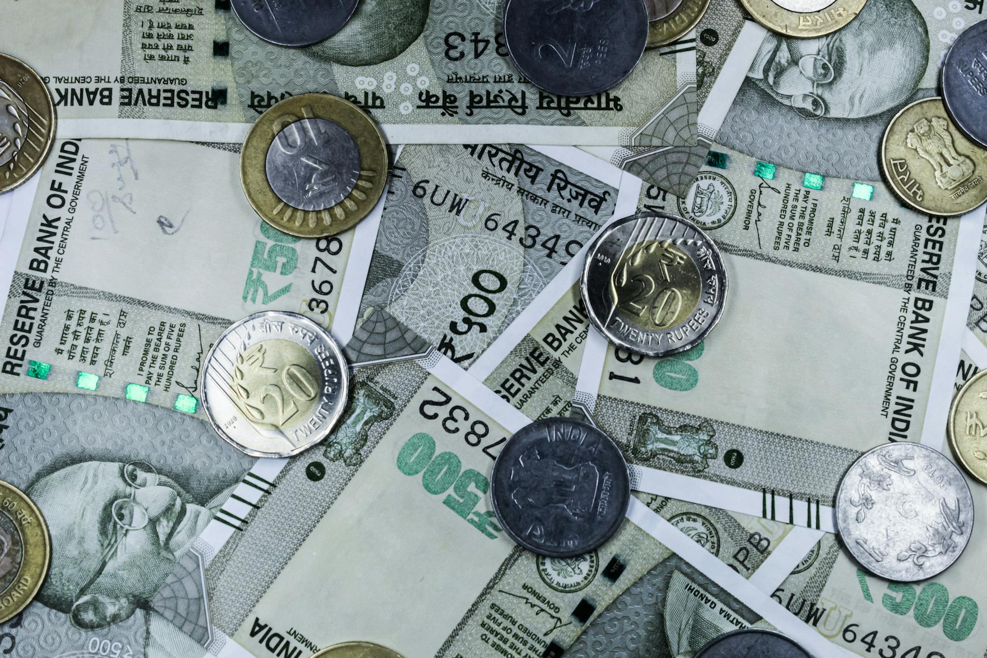 Top view of various Indian rupee banknotes and coins, highlighting financial themes.