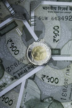 Close-up of Indian 500 rupee banknotes with a rupee coin on top, showcasing currency and wealth.