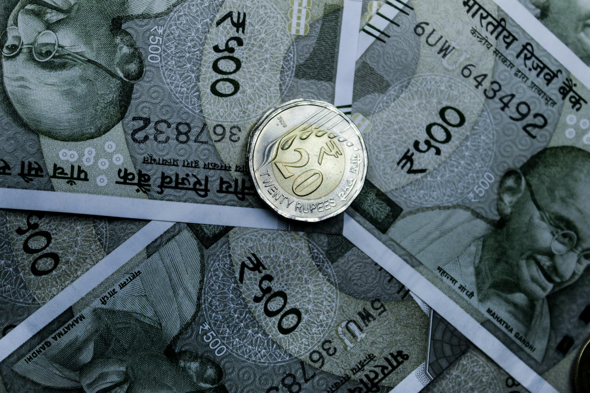 Detailed close-up of Indian 500-rupee notes and a 20-rupee coin, highlighting currency details.