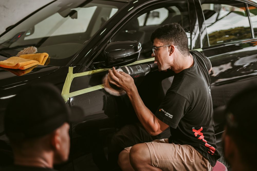 Detailing technician polishing a black car panel