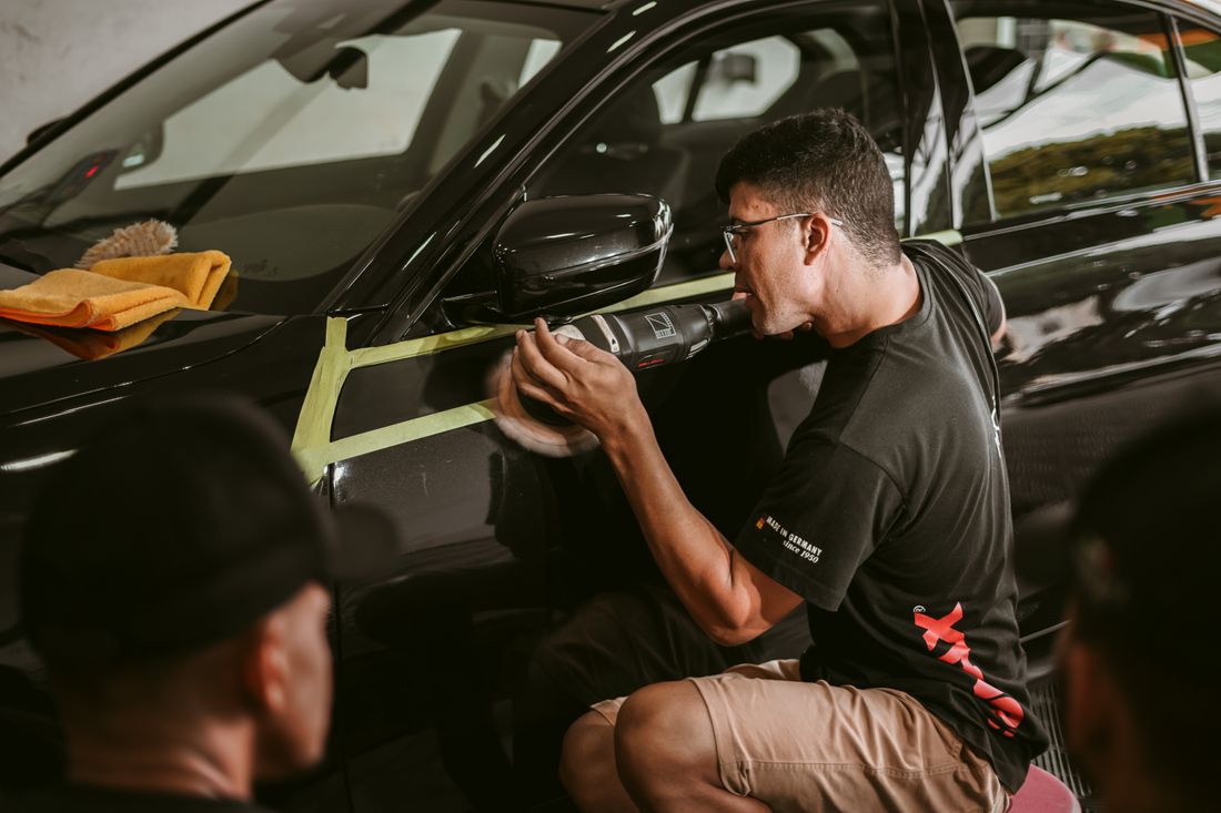Detailer machine-polishing a car panel during a full detail