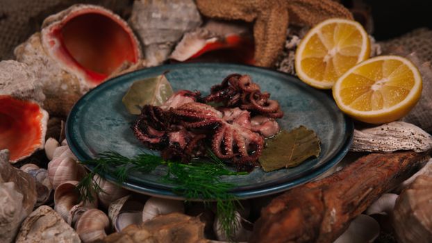 Delicious fresh octopus with lemon halves on a plate surrounded by seashells, perfect for seafood lovers.