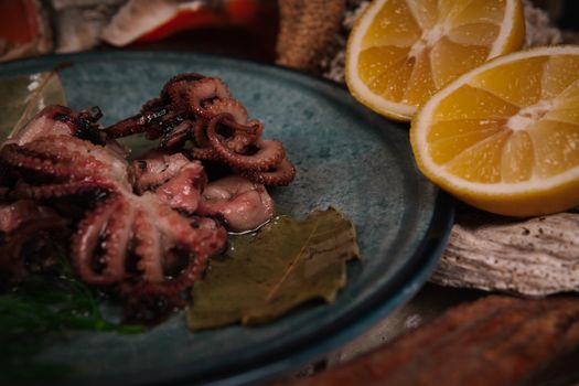 Gourmet octopus dish served with bay leaves and lemon slices on a rustic plate.