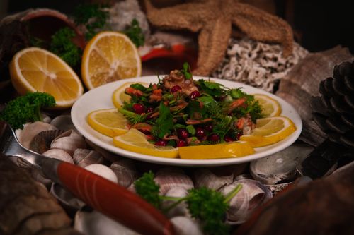 Free Vibrant salad with fresh herbs, walnuts, and lemon slices on a decorative plate. Stock Photo
