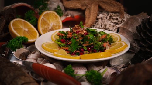 Free Vibrant salad with fresh herbs, walnuts, and lemon slices presented in a rustic setting. Stock Photo