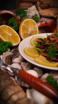 Colorful salad with lemon garnish on a plate surrounded by shells and greenery.