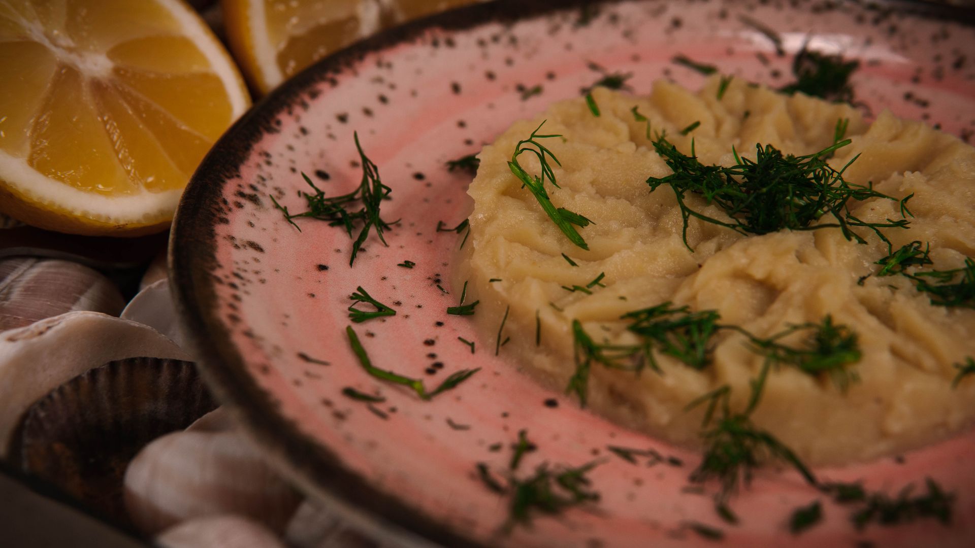 Close-up of a Mediterranean mezze dish garnished with fresh dill and lemon slices, captured in warm tones.