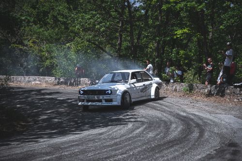 Free A vintage car drifting around a forest track corner as spectators watch the motorsport event. Stock Photo