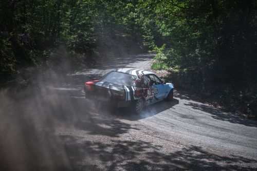 Free A racecar expertly drifts through a forest dirt road, kicking up dust and showcasing speed. Stock Photo