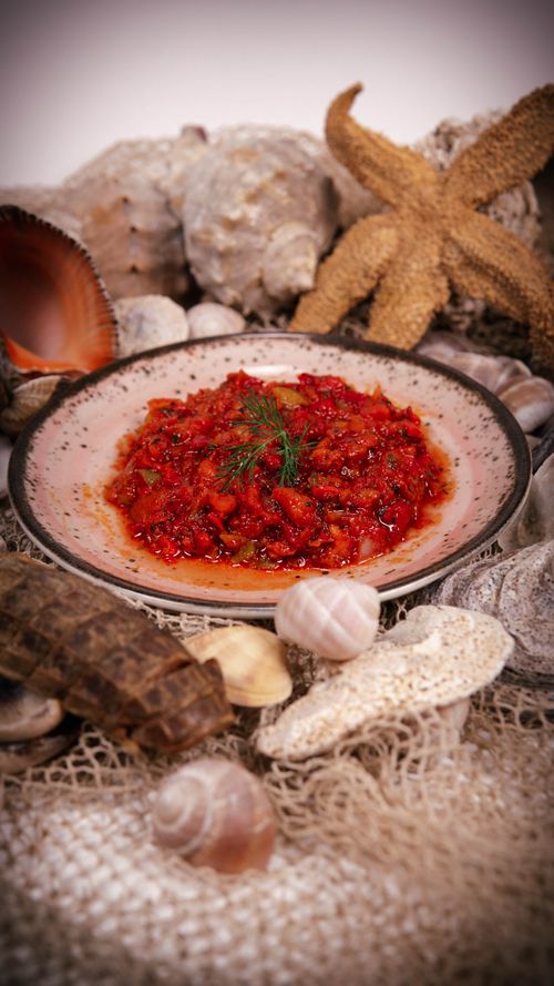 Free Close-up of delicious spicy seafood salsa garnished with dill, surrounded by decorative sea shells. Stock Photo