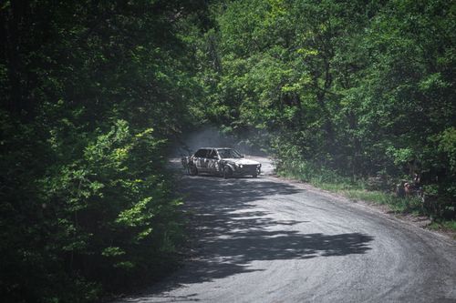 Free Race car drifting on a forest road curve with green trees in the background. Stock Photo