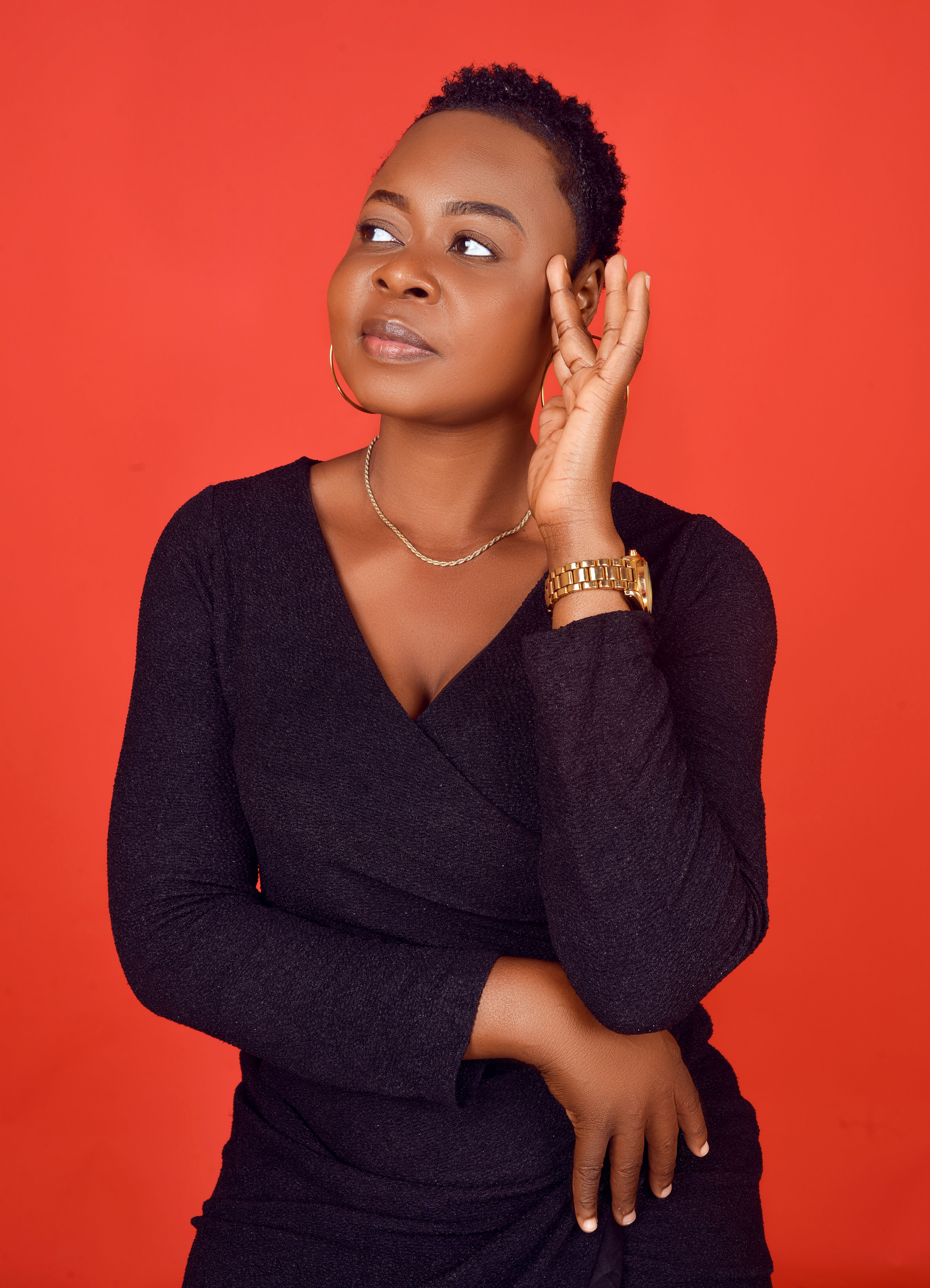 Studio portrait of a black woman in a black dress against a vibrant red background.