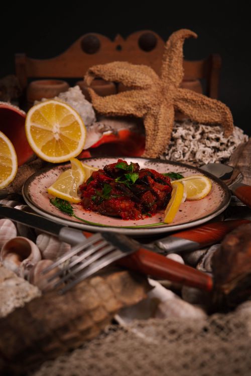 Free Elegant seafood dish garnished with lemons and herbs, surrounded by shells, captured in an artistic setting. Stock Photo