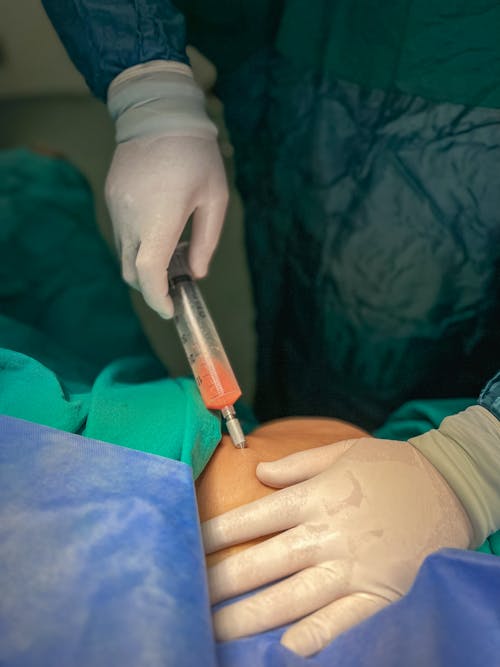 Hands in Gloves Applying Syringe