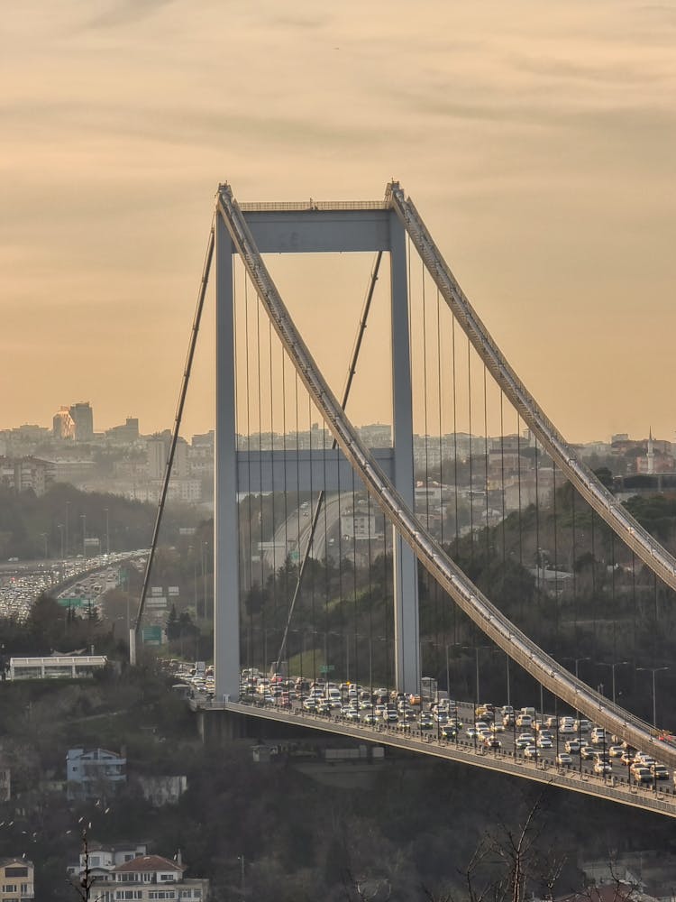 Cars Driving On Suspension Bridge On Sunset