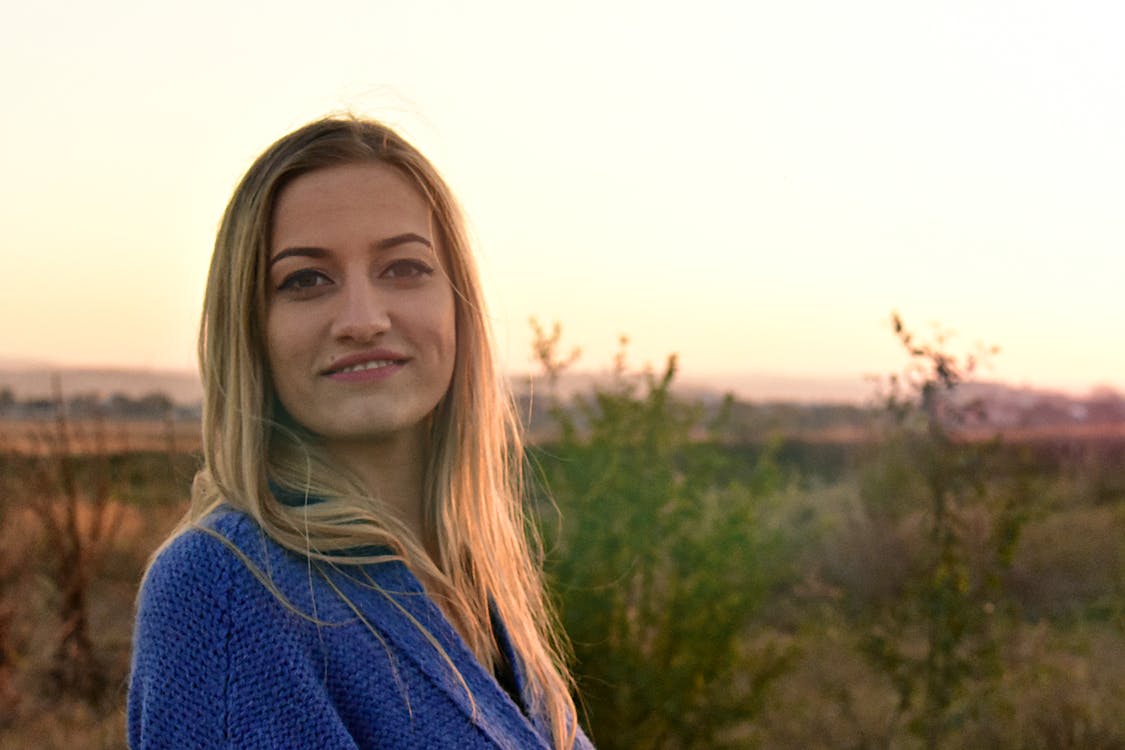 Woman in Blue Knit Top Smiling Outdoors