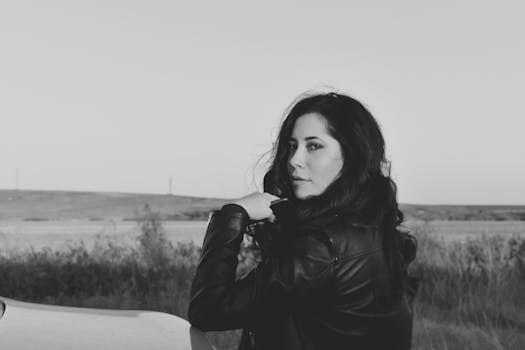 Black and white portrait of a woman in a leather jacket outdoors.