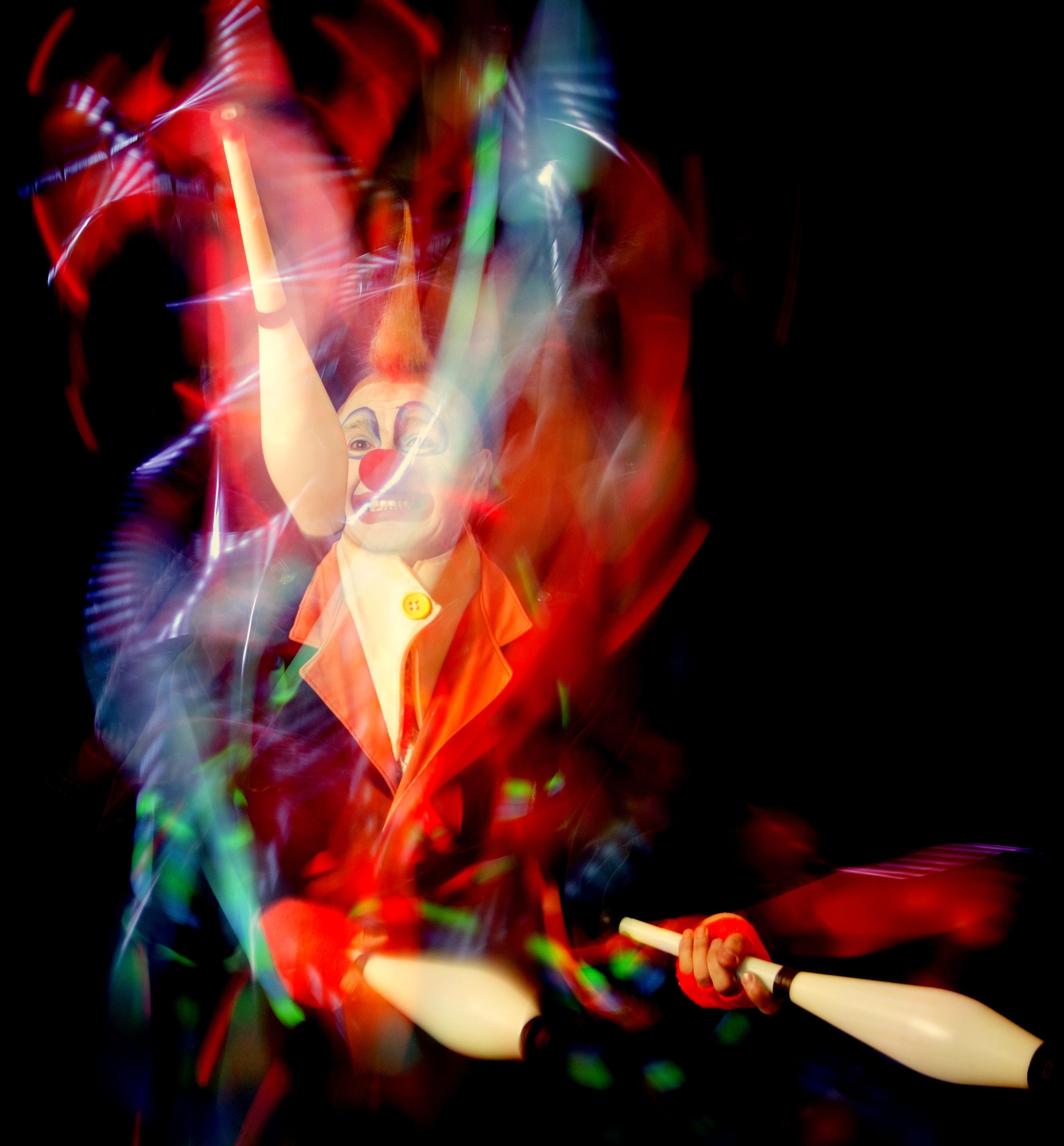 Colorful and dynamic photo of a clown juggling, capturing motion and vibrant energy in a studio setting.