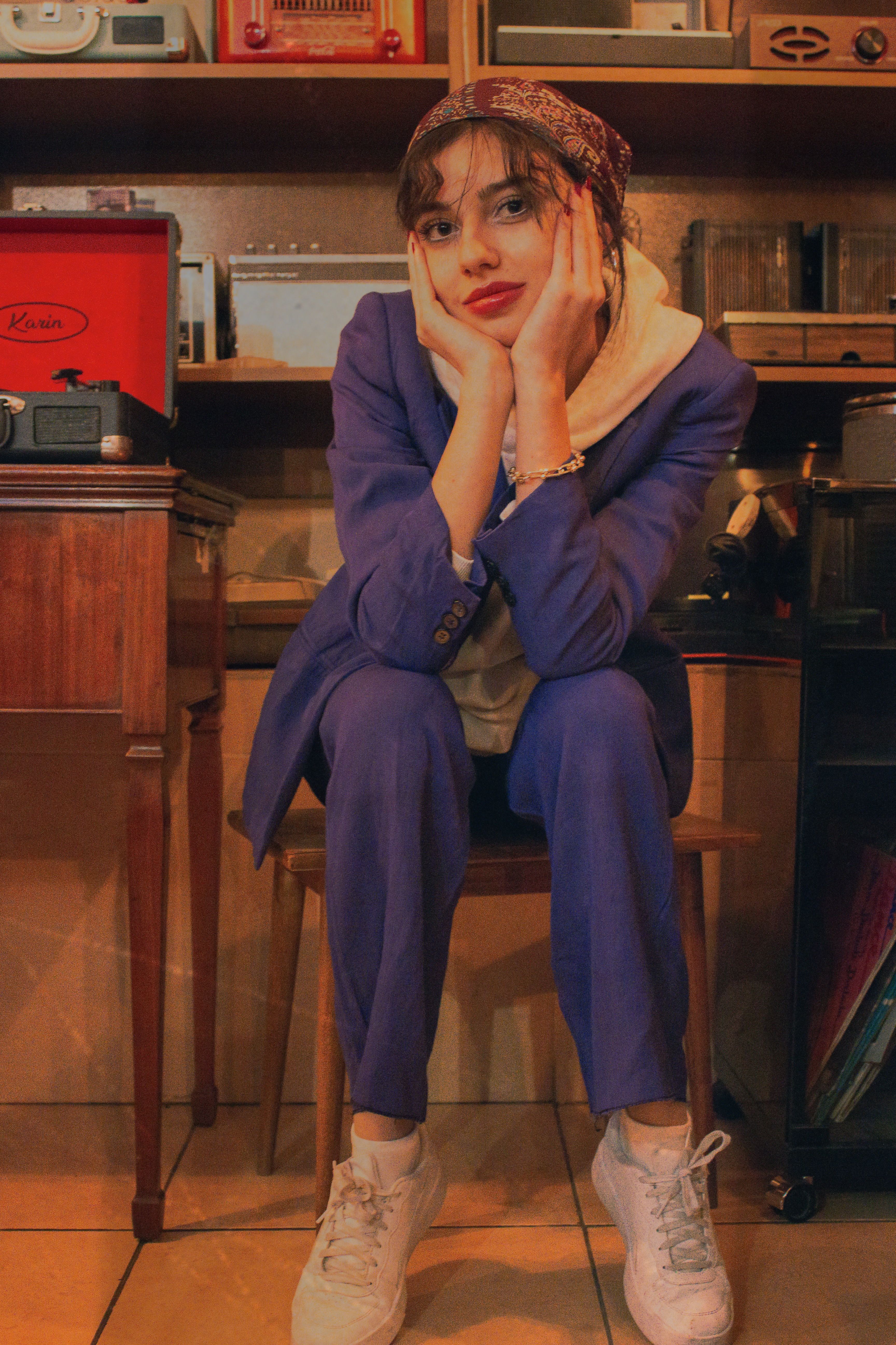 A woman in casual retro attire sits pensively in a vintage record room.