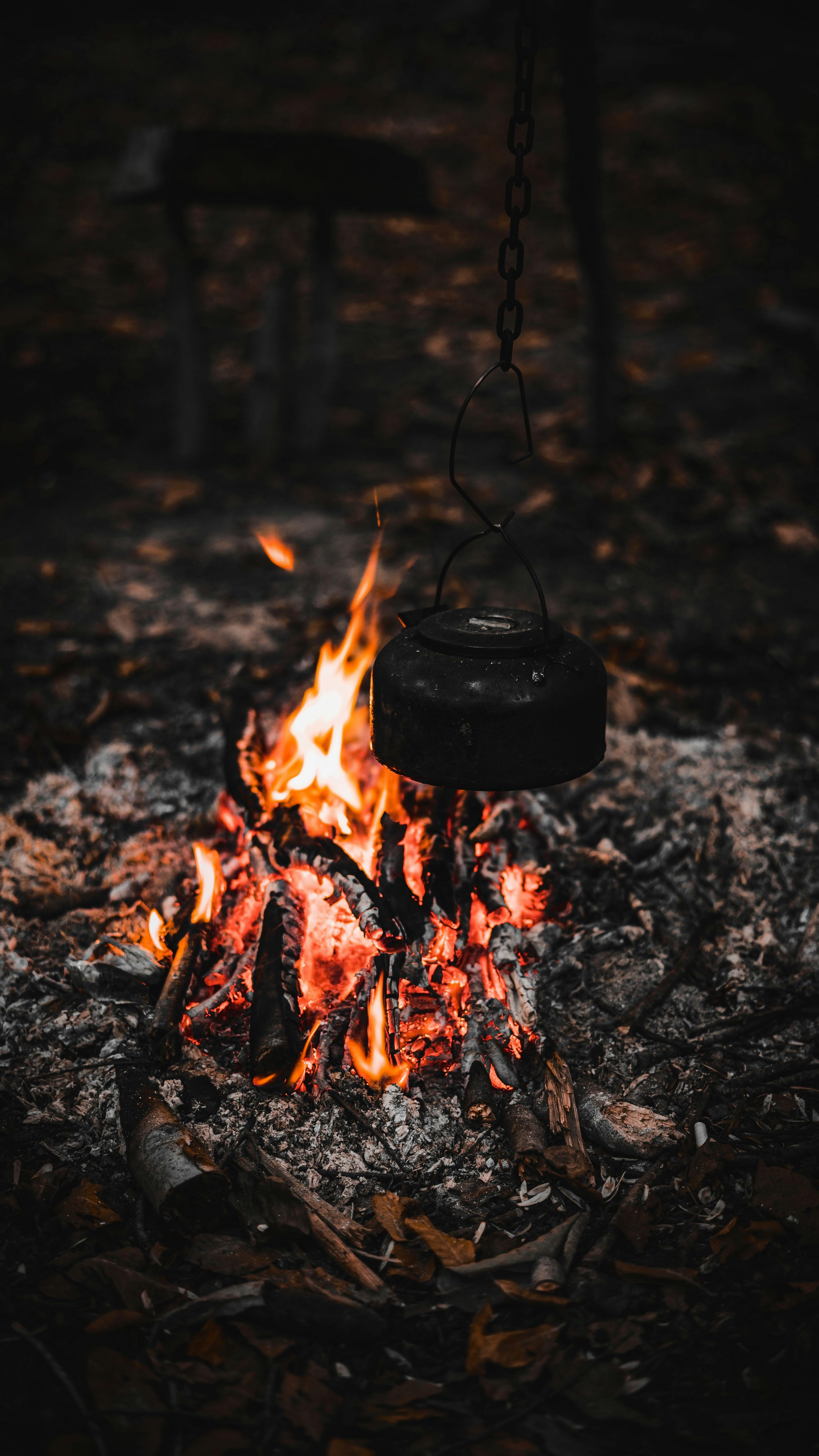 Campfire kettle closeup with blurred bonfire in the background