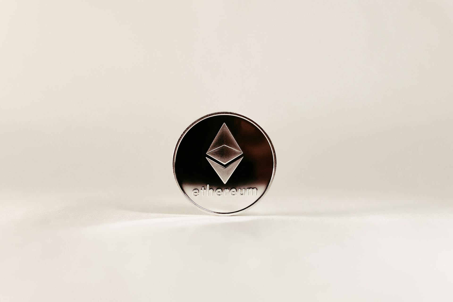 Close-up of a shiny Ethereum coin with a minimalist white background, ideal for finance topics.