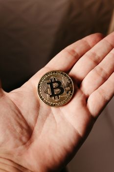 A detailed view of a Bitcoin coin resting in a human hand, symbolizing cryptocurrency.